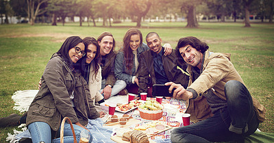 Buy stock photo Shot of young friends having a picnic outside
