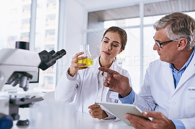 Buy stock photo Shot of two scientists conducting an experiment together in a lab