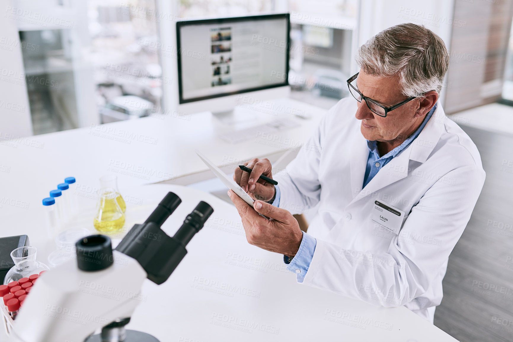 Buy stock photo Shot of a mature scientist working on a digital tablet in a lab