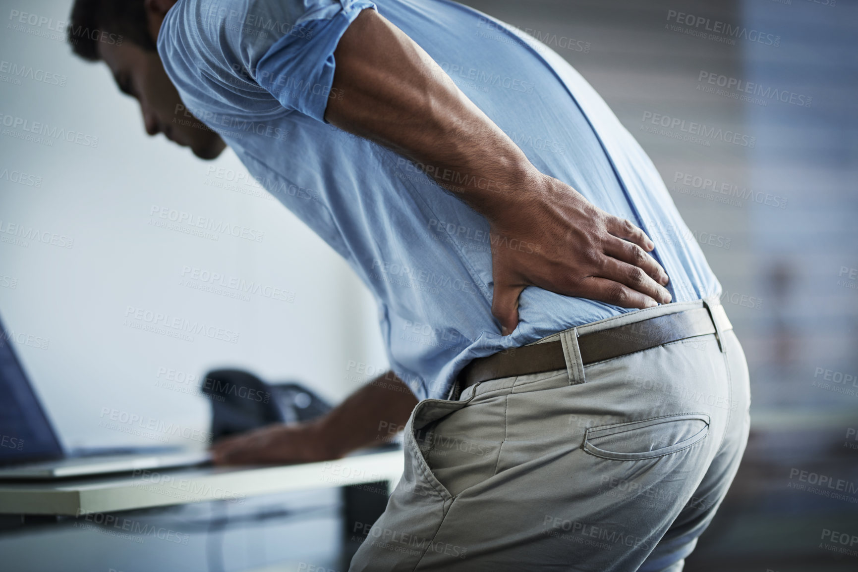 Buy stock photo Shot of a young businessman suffering with back pain at work