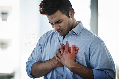 Buy stock photo Shot of a young businessman suffering with chest pain at work