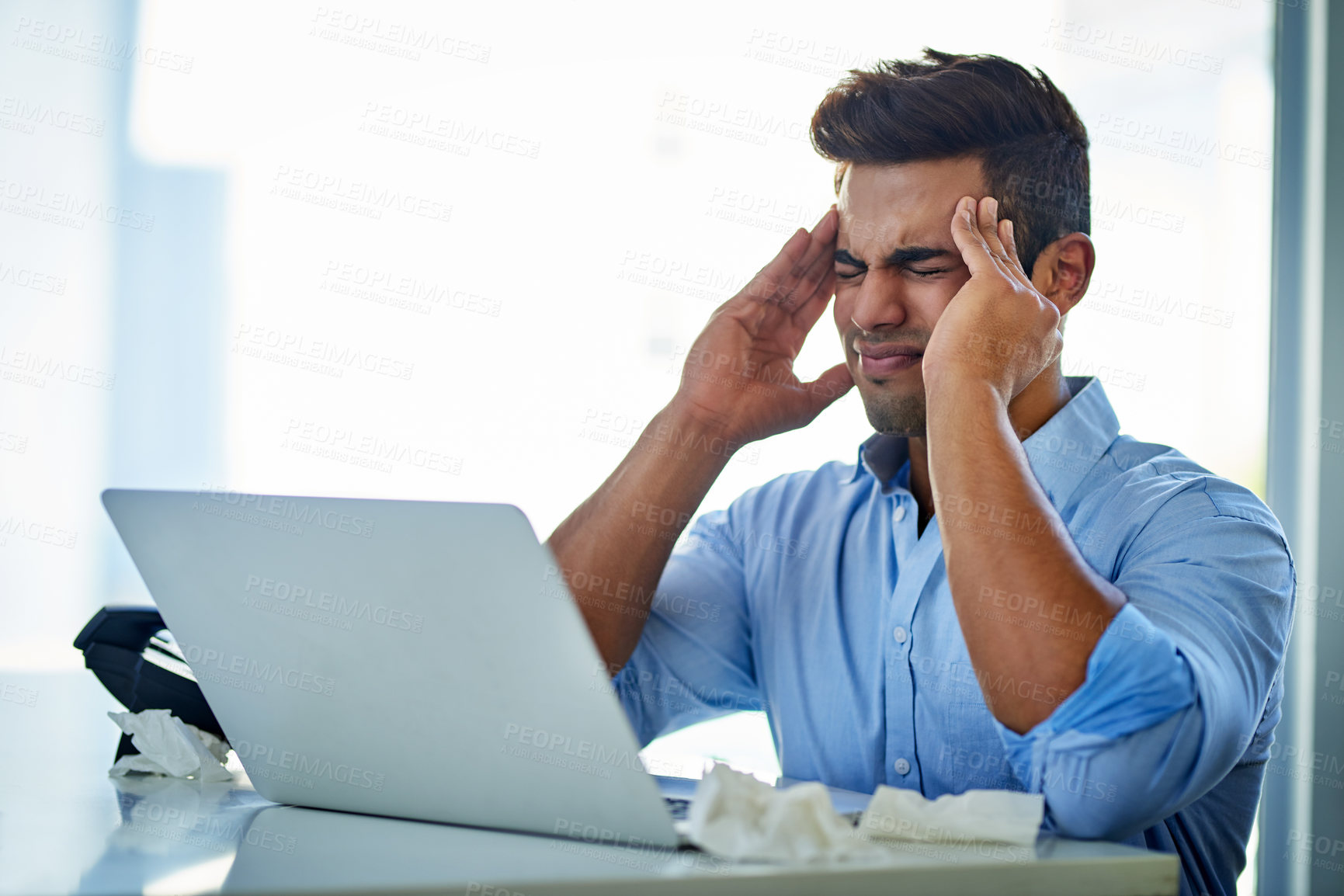 Buy stock photo Shot of a young businessman suffering with a headache at work