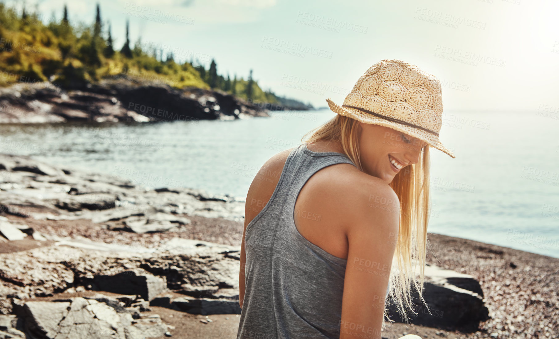 Buy stock photo Woman, smile and relax at lake for holiday, freedom or outdoor adventure in nature with trees. Female person, happiness or calm by water for vacation in Canada, wellness and peace for travel with hat