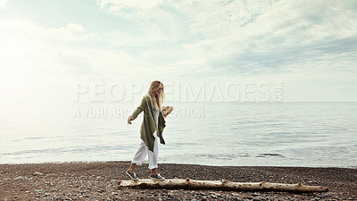 Buy stock photo Shot of a young woman walking along a log at a lake
