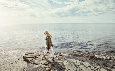 Buy stock photo Woman, walking and beach with sunshine for outdoor holiday, weeken or journey in nature. Back view of female person strolling on rock or ocean coast by water for travel, vacation or freedom at sea