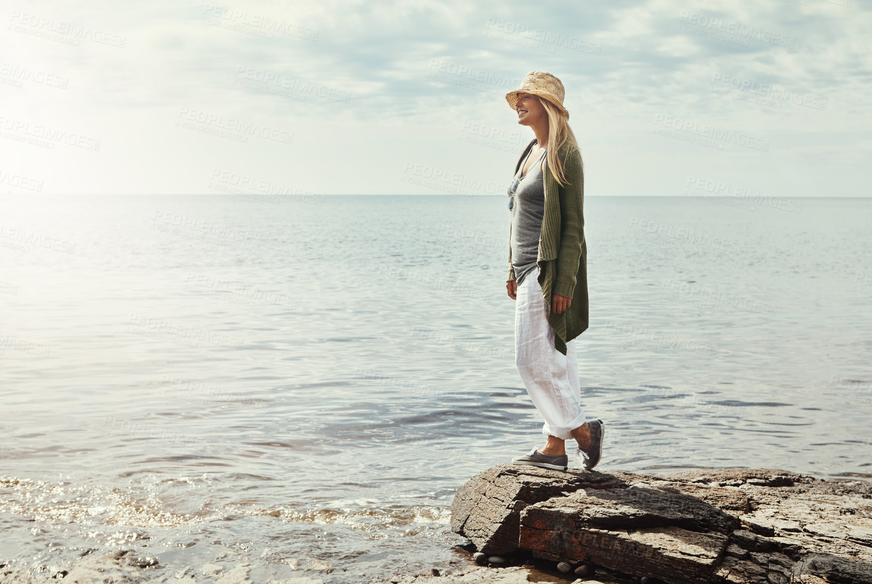 Buy stock photo Happy woman, thinking and beach with sunshine in nature for outdoor holiday, weekend or journey. Young female person on rock with smile for travel, vacattion or freedom by ocean coast, water or sea