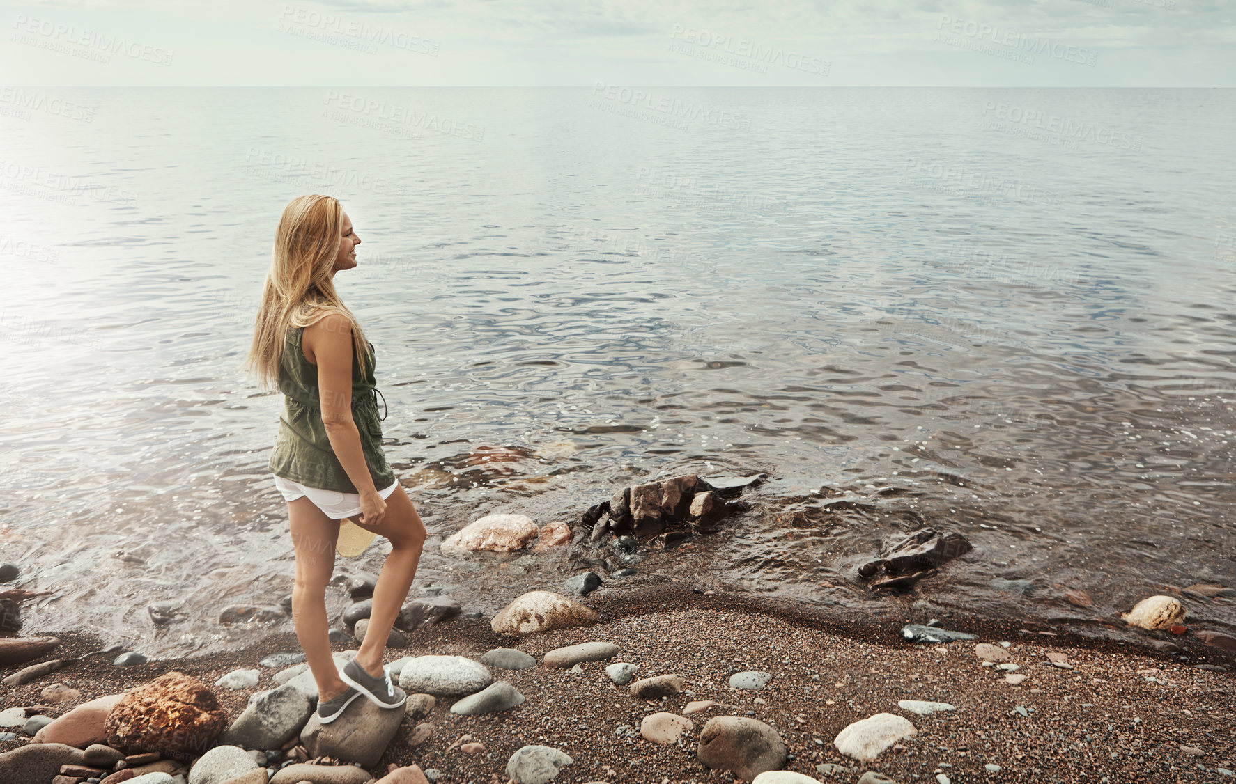 Buy stock photo Shot of an attractive young woman spending a day at the lake