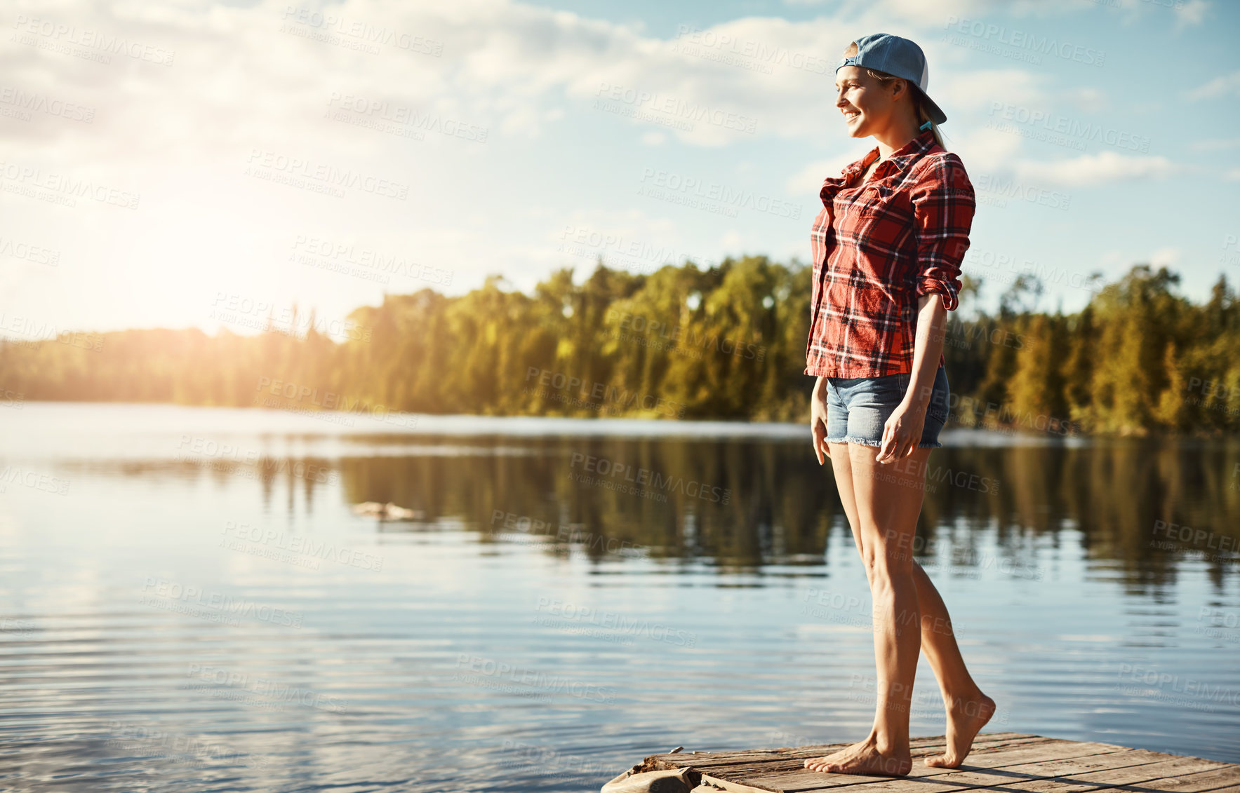 Buy stock photo Shot of a happy young woman spending time by the lakeside