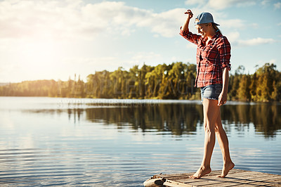 Buy stock photo Shot of a happy young woman spending time by the lakeside