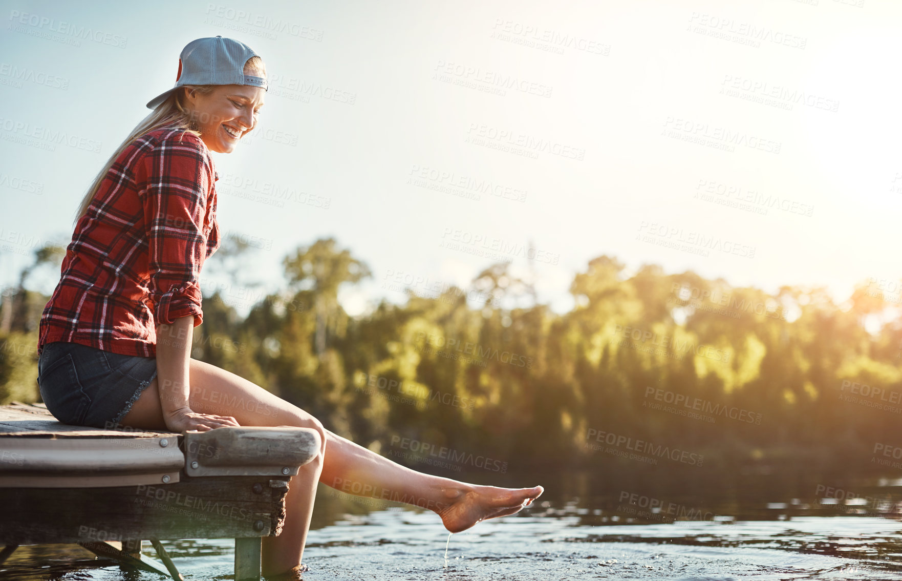 Buy stock photo Shot of a happy young woman spending time by the lakeside