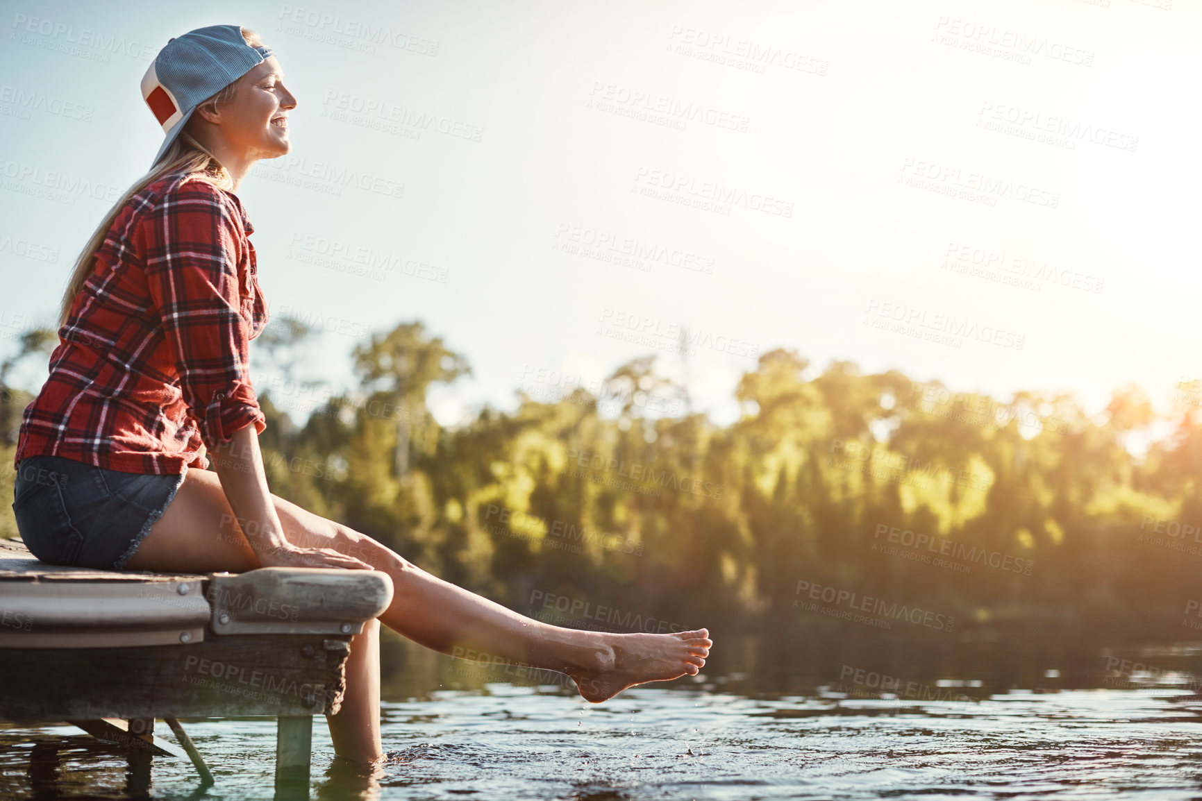 Buy stock photo Shot of a happy young woman spending time by the lakeside