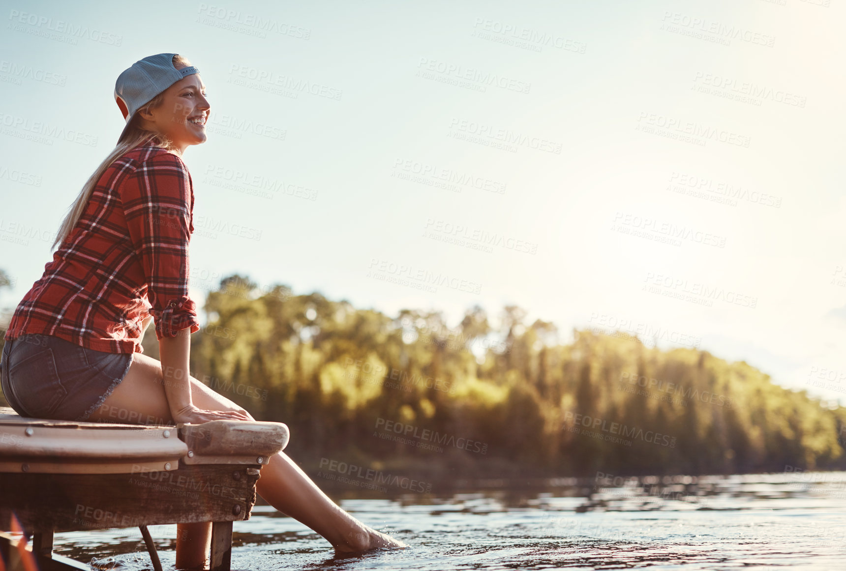 Buy stock photo Shot of a happy young woman spending time by the lakeside