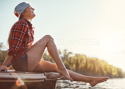 Buy stock photo Shot of a happy young woman spending time by the lakeside