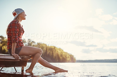 Buy stock photo Shot of a happy young woman spending time by the lakeside