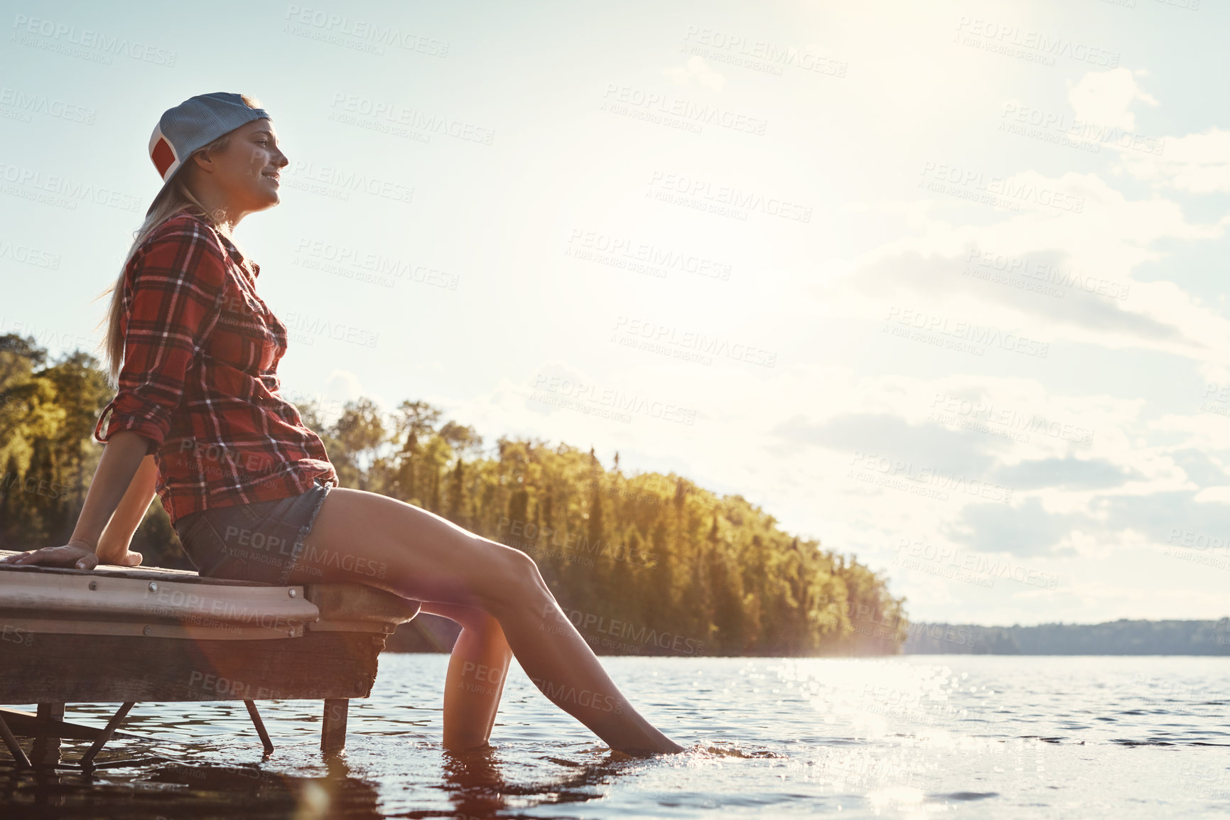 Buy stock photo Shot of a happy young woman spending time by the lakeside