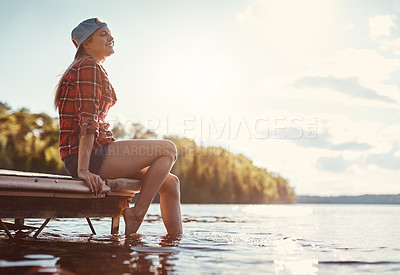 Buy stock photo Shot of a happy young woman spending time by the lakeside