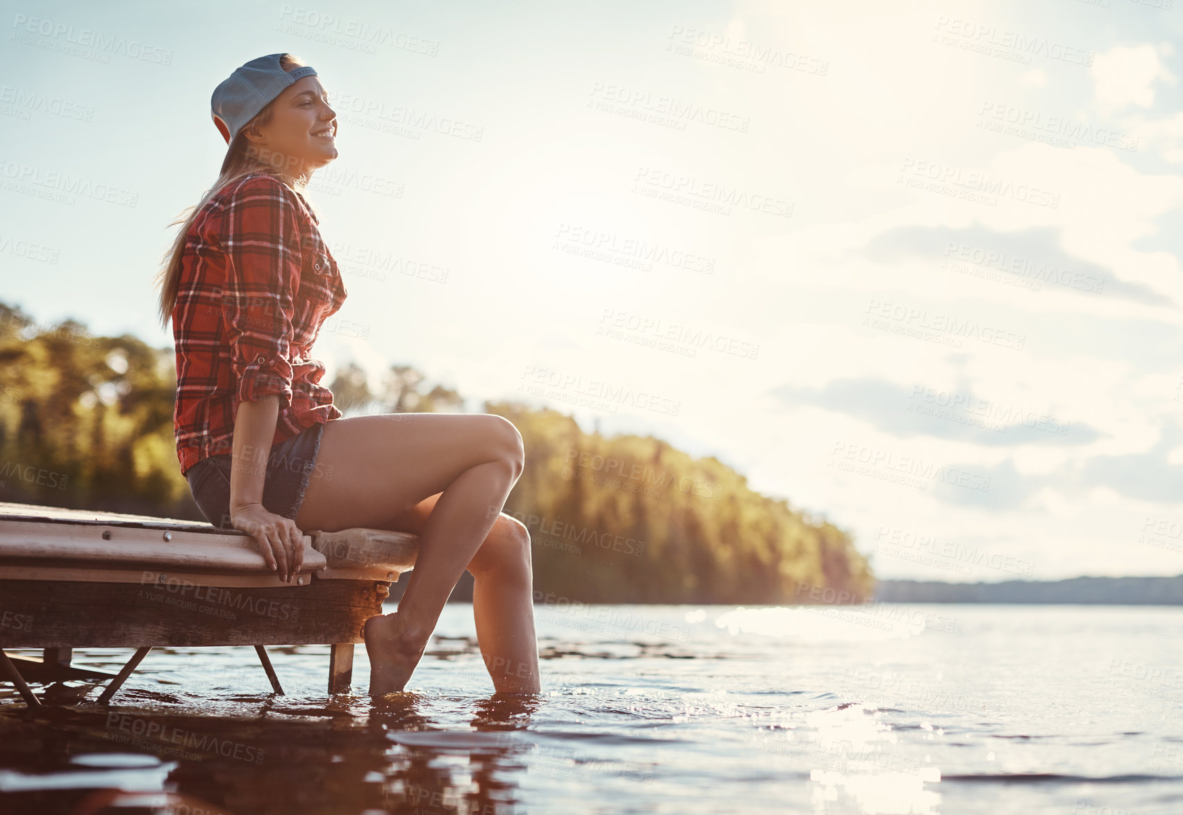 Buy stock photo Shot of a happy young woman spending time by the lakeside