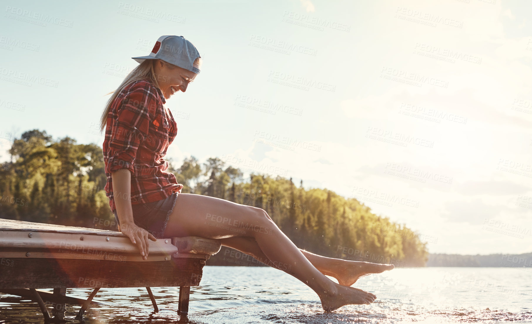 Buy stock photo Shot of a happy young woman spending time by the lakeside