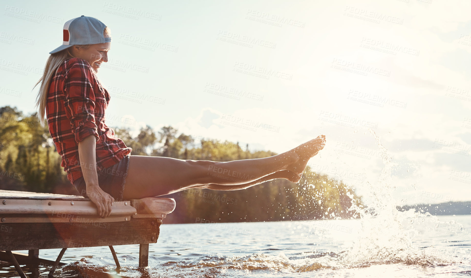 Buy stock photo Shot of a happy young woman spending time by the lakeside