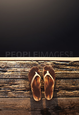 Buy stock photo High angle shot of a pair of thongs on the edge of a jetty