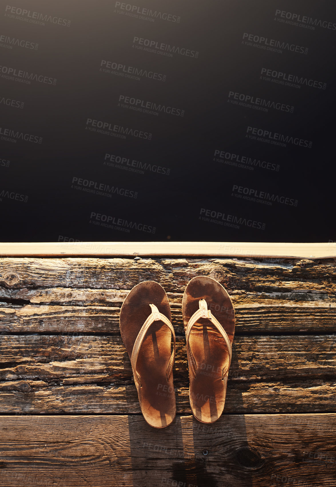 Buy stock photo High angle shot of a pair of thongs on the edge of a jetty