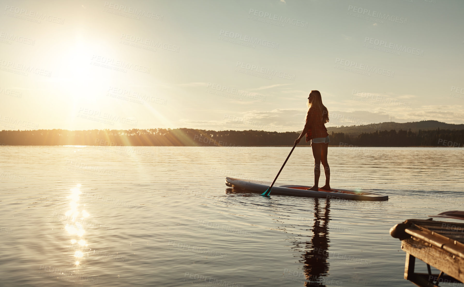 Buy stock photo Lake, sunset and woman on paddle board for relax, water sports and vacation on river for tourism. Sunlight, summer and holiday in Germany for adventure and balance practice, swimsuit and travel