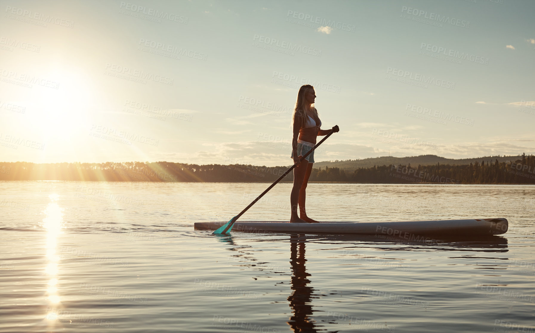 Buy stock photo Lake, sunset and woman on paddle board for relax, water sports and vacation on river for tourism. Sunlight, summer and holiday in Germany for female person, swimsuit and travel fitness for adventure