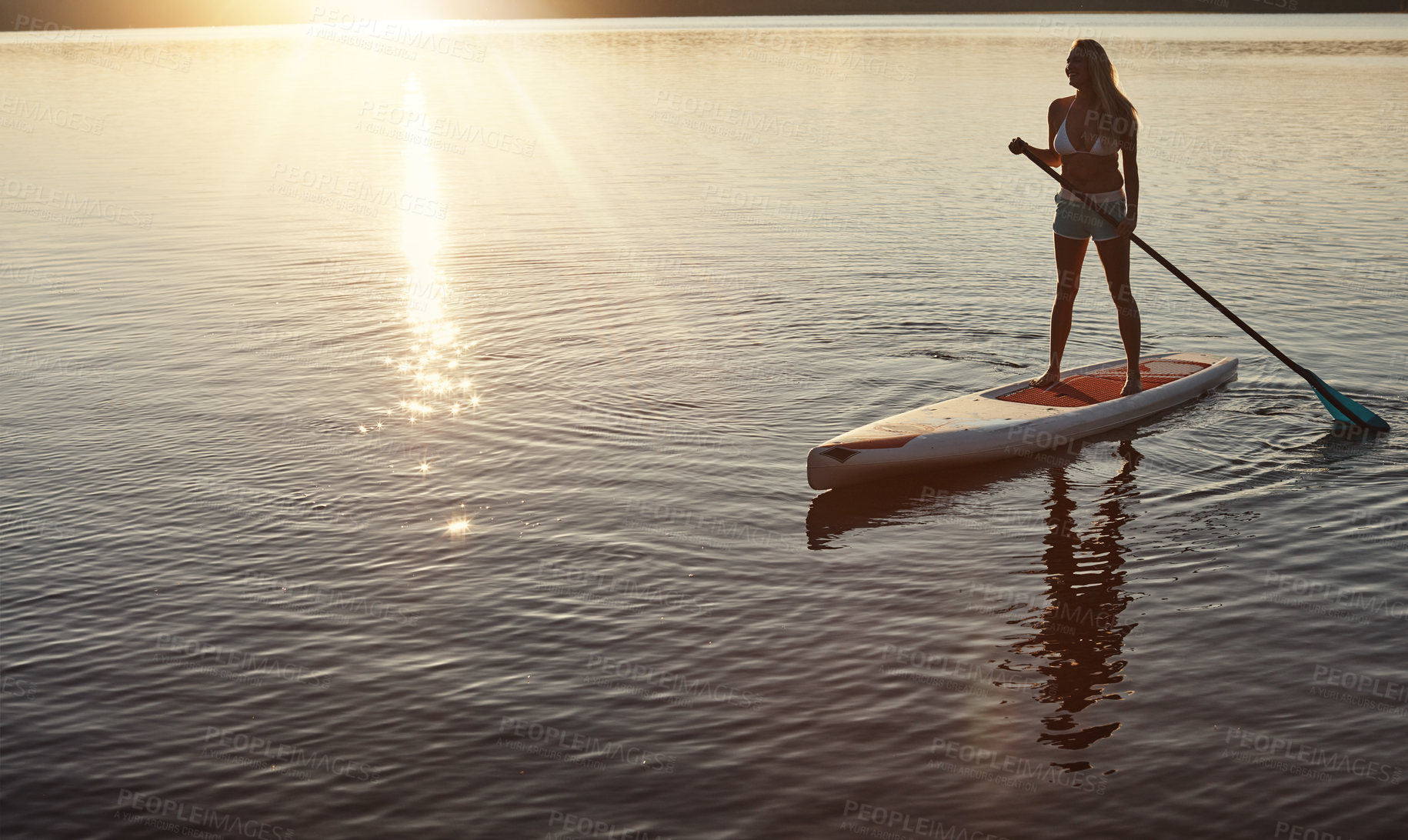 Buy stock photo Lake, sunset and woman on paddle board for relax, water sports and vacation on river for tourism. Sunlight, summer and holiday in Germany for female person, swimsuit and travel fitness for adventure