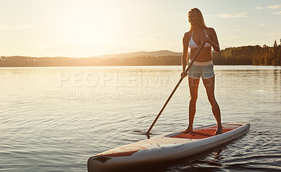 Buy stock photo Lake, sunset and woman on paddle board for exercise, water sport and vacation on river for tourism. Sunshine, summer and holiday in Germany for female person, swimsuit or travel fitness for adventure