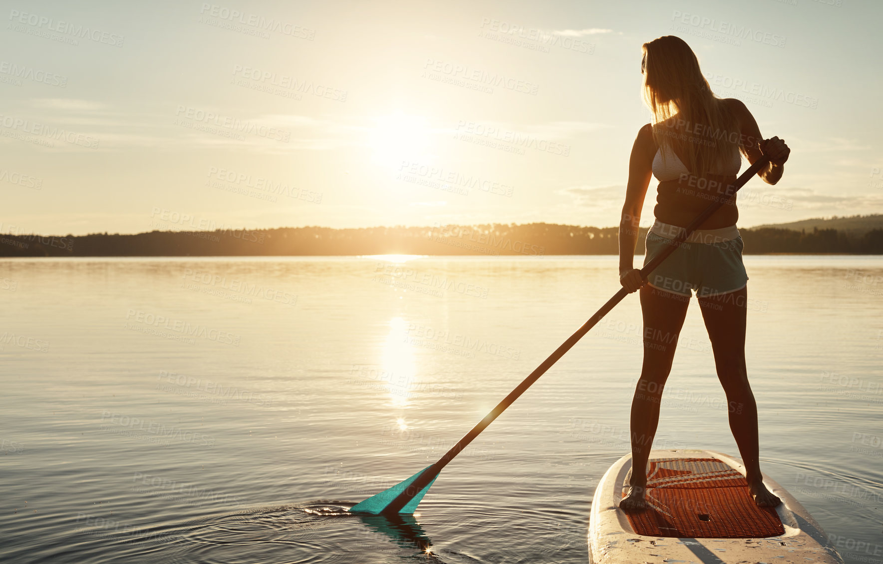 Buy stock photo Lake, sunset and woman on paddle board for balance, water sport and vacation on river for tourism. Nature, summer or holiday in Germany for female person, swimsuit or travel exercise for adventure