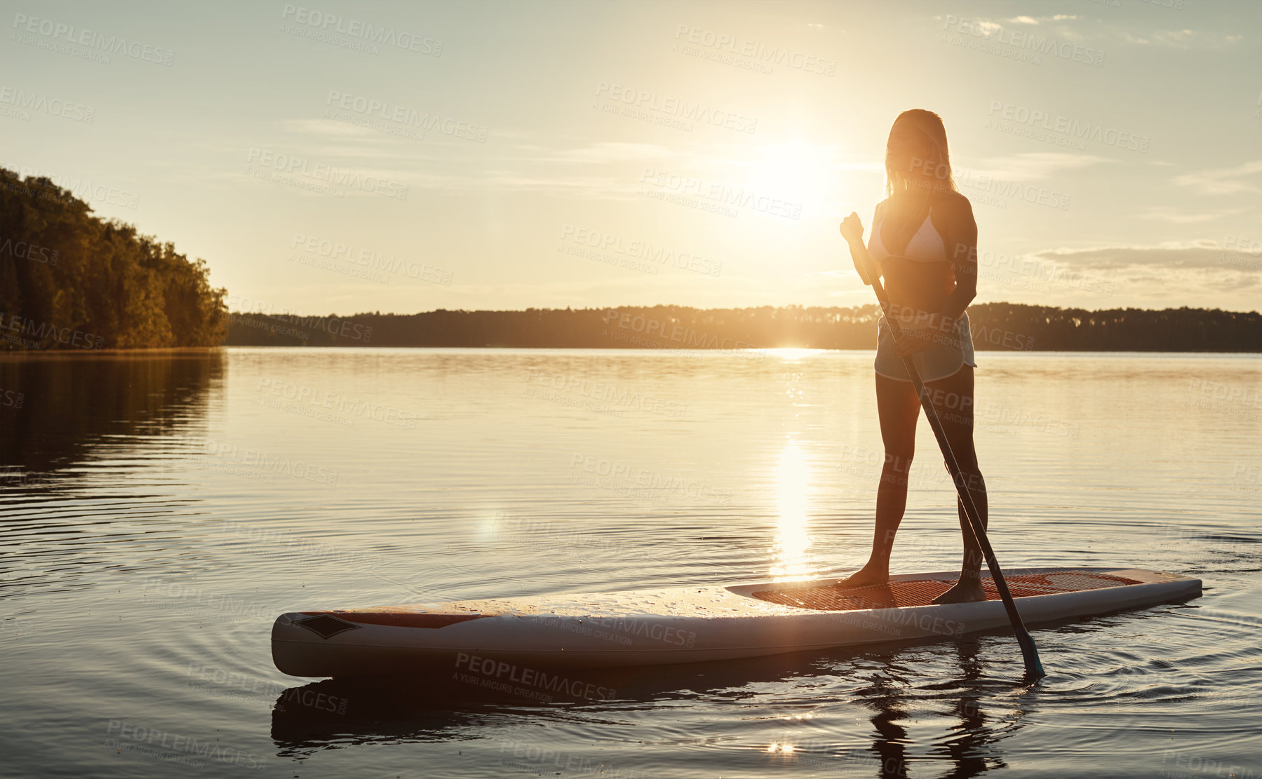 Buy stock photo Lake, sunset and woman on paddle board for balance, water sport and vacation on river for tourism. Nature, summer or holiday in Germany for female person, swimsuit or travel exercise for adventure