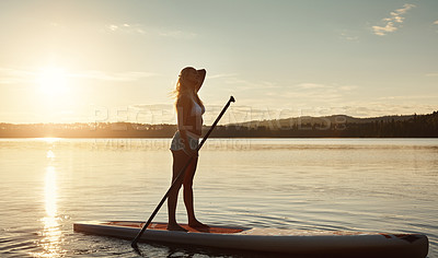 Buy stock photo Lake, sunset and woman on paddle board for balance, water sport and vacation on river for tourism. Nature, summer or holiday in Germany for female person, swimsuit or travel exercise for adventure