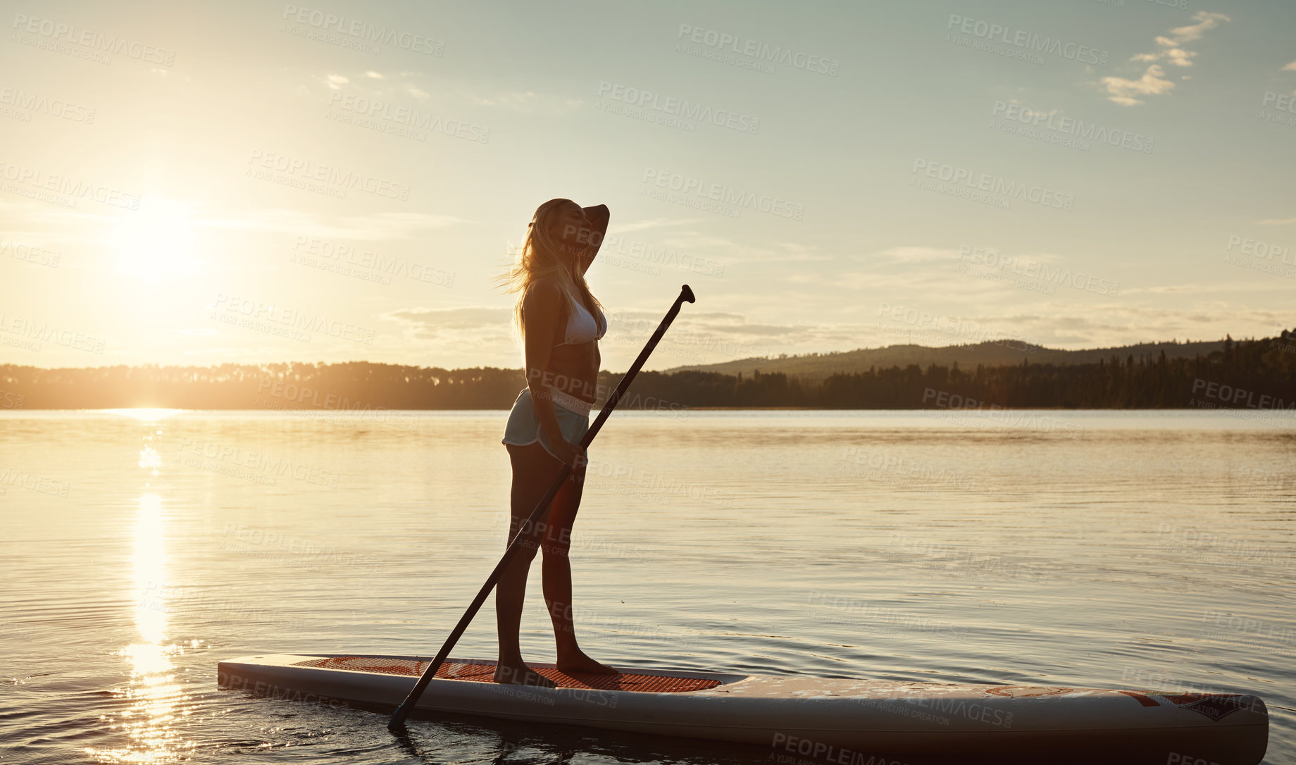 Buy stock photo Lake, sunset and woman on paddle board for balance, water sport and vacation on river for tourism. Nature, summer or holiday in Germany for female person, swimsuit or travel exercise for adventure