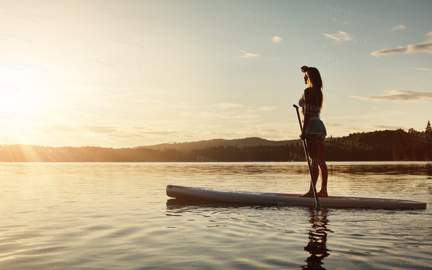 Buy stock photo Lake, sunshine and woman on paddle board with trees, water sport and vacation on river for tourism. Exercise, sunrise or holiday in Germany for female person, view and travel fitness for adventure