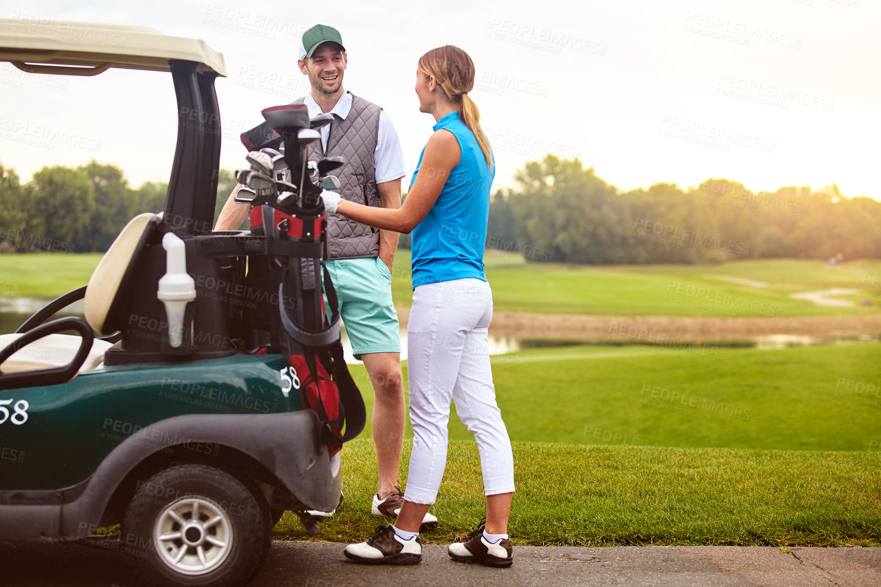Buy stock photo Talking, golf course and couple with love, support and bonding together with hobby. Outdoor, players and man with woman, conversation and happiness with game, weekend break and equipment for fun