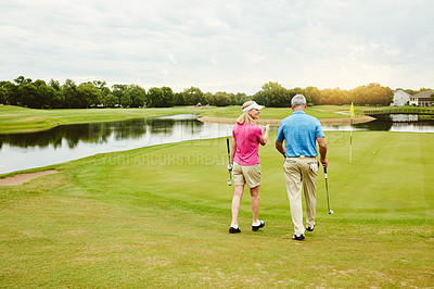 Buy stock photo Mature couple, club and walking for golf game outdoor, talking and sports support of recreation practice. Woman, man and love for hobby lesson, advice or discussion of retirement activity in nature