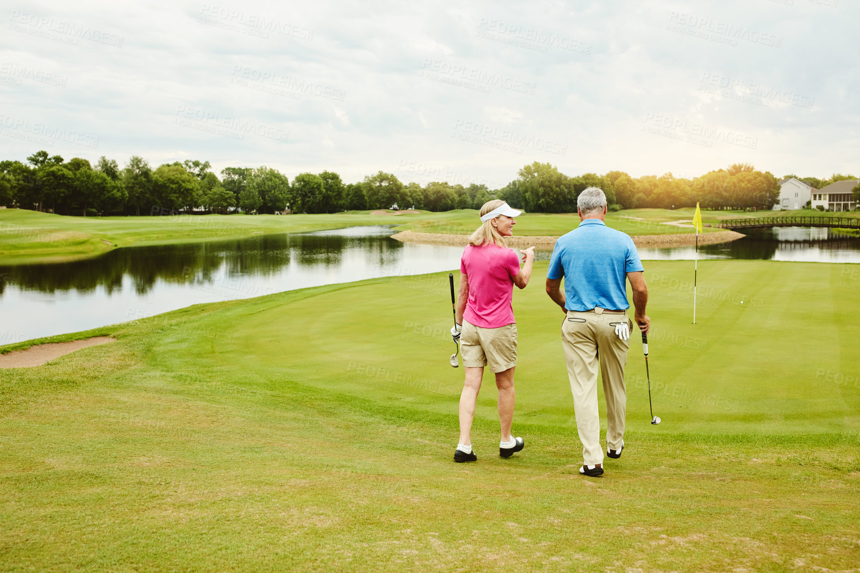 Buy stock photo Mature couple, club and walking for golf game outdoor, talking and sports support of recreation practice. Woman, man and love for hobby lesson, advice or discussion of retirement activity in nature