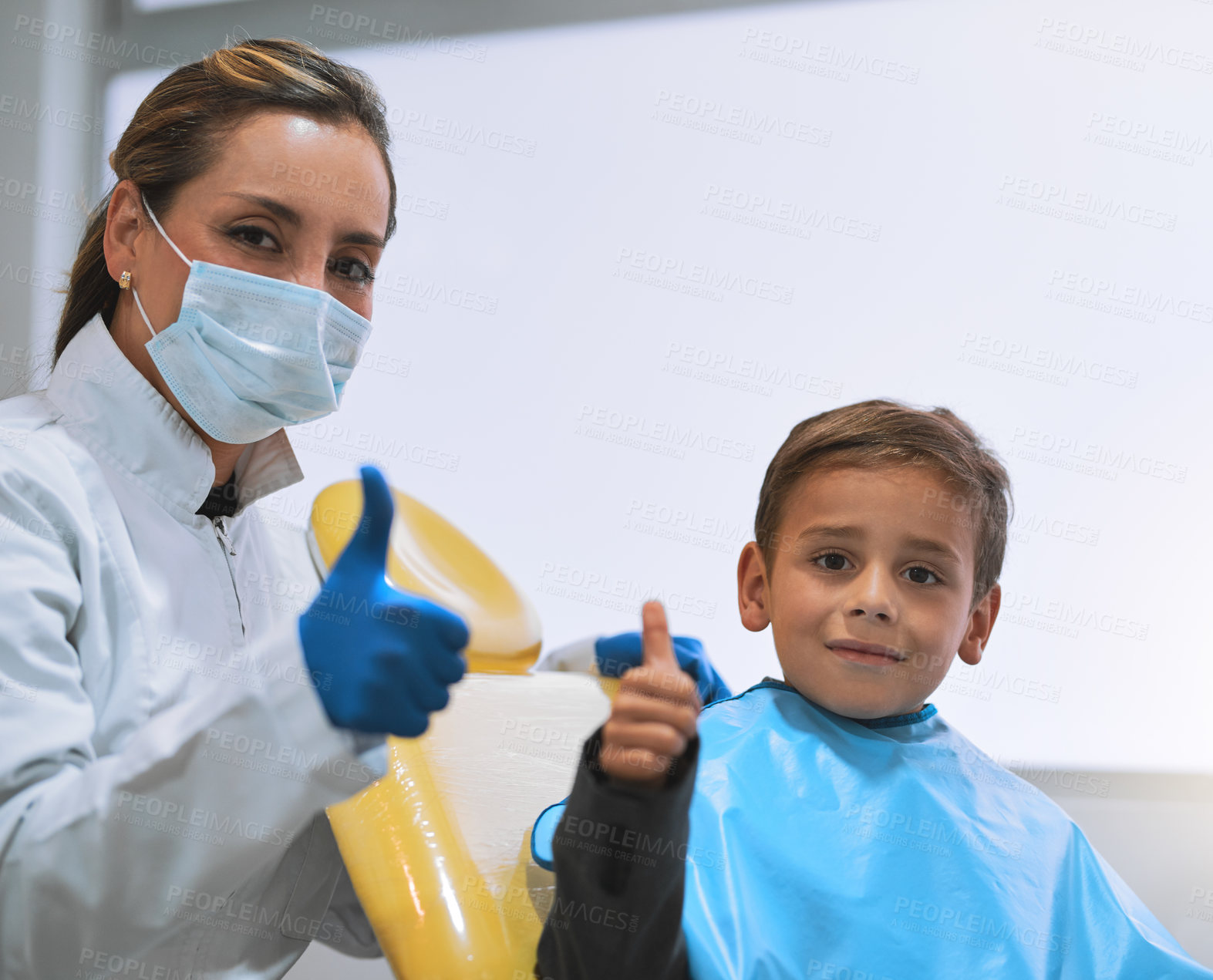 Buy stock photo Portrait of a cheerful young female dentist and her young little patient getting ready for a checkup while showing thumbs up