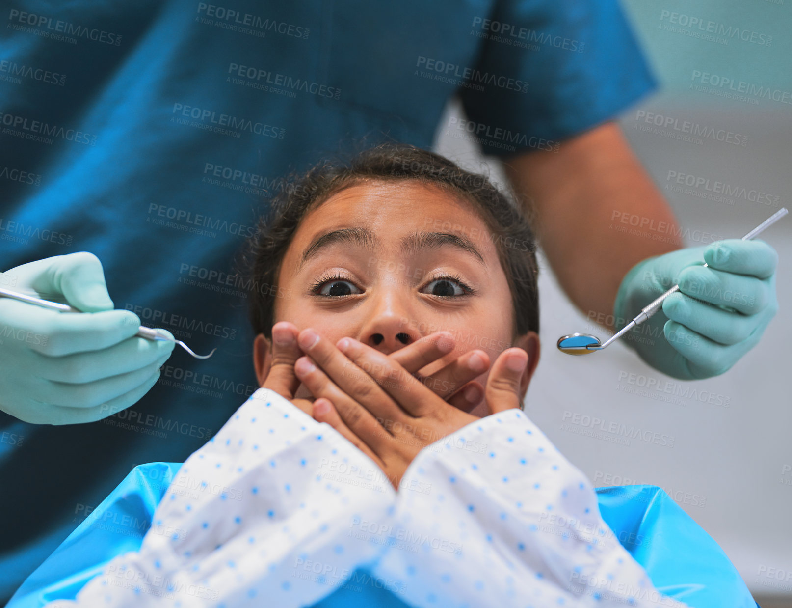 Buy stock photo Shot of a frightened little girl lying down on a dentist chair and holds her mouth closed to keep the dentist from working on her