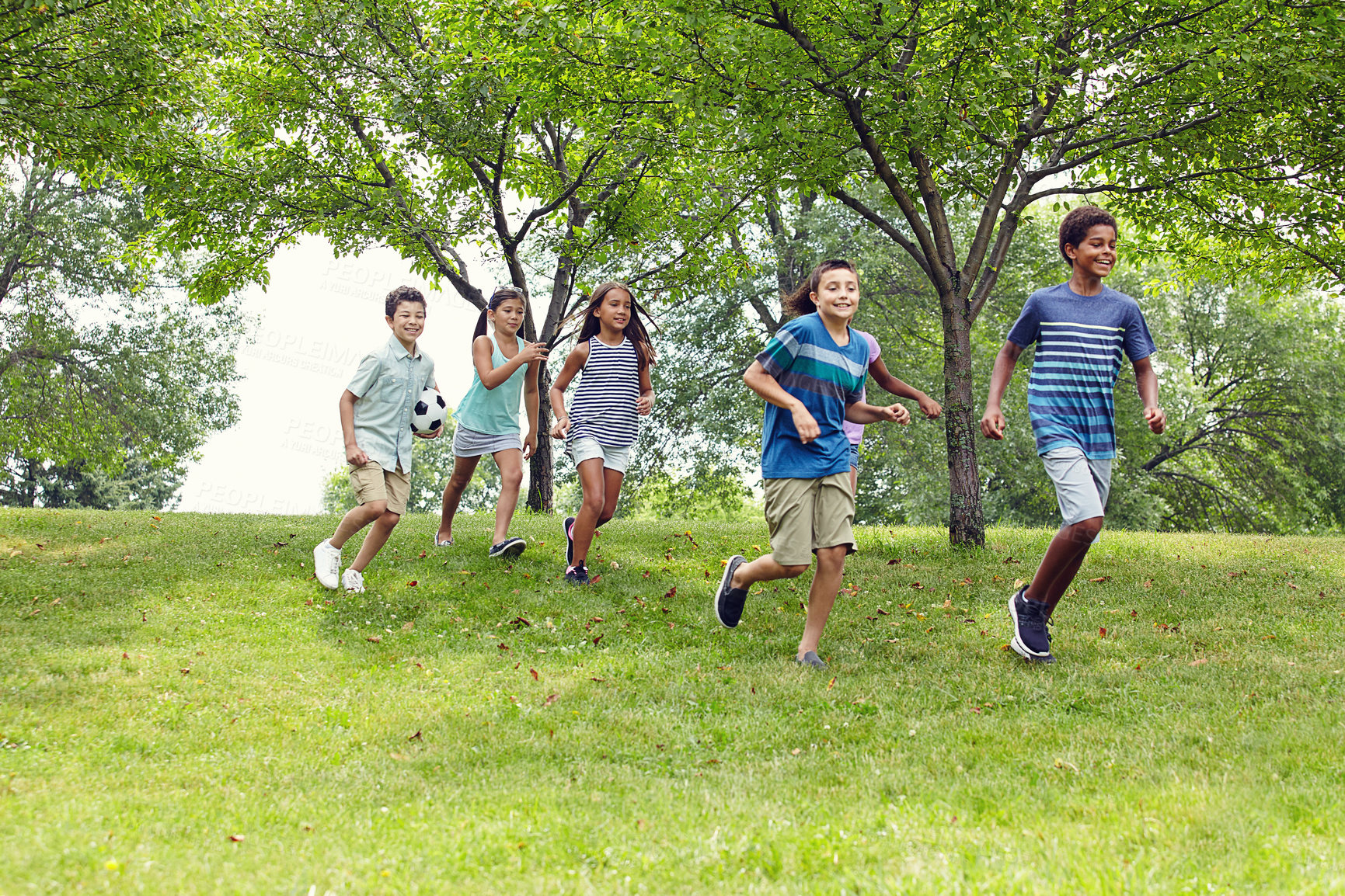 Buy stock photo Shot of a group of young friends running down an embankment in the park