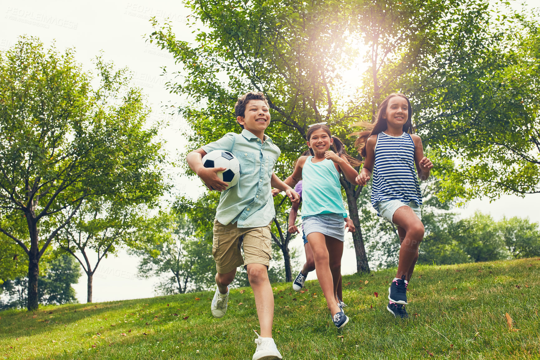 Buy stock photo Shot of a group of young friends running down an embankment in the park