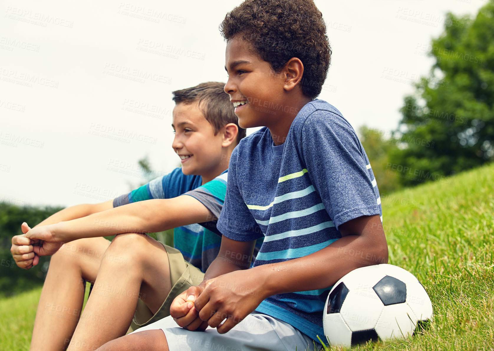 Buy stock photo Children, friends and sitting on grass with soccer ball in park for happiness, development or bonding together. Boys, nature and young kids with smile for freedom, support or relax on weekend