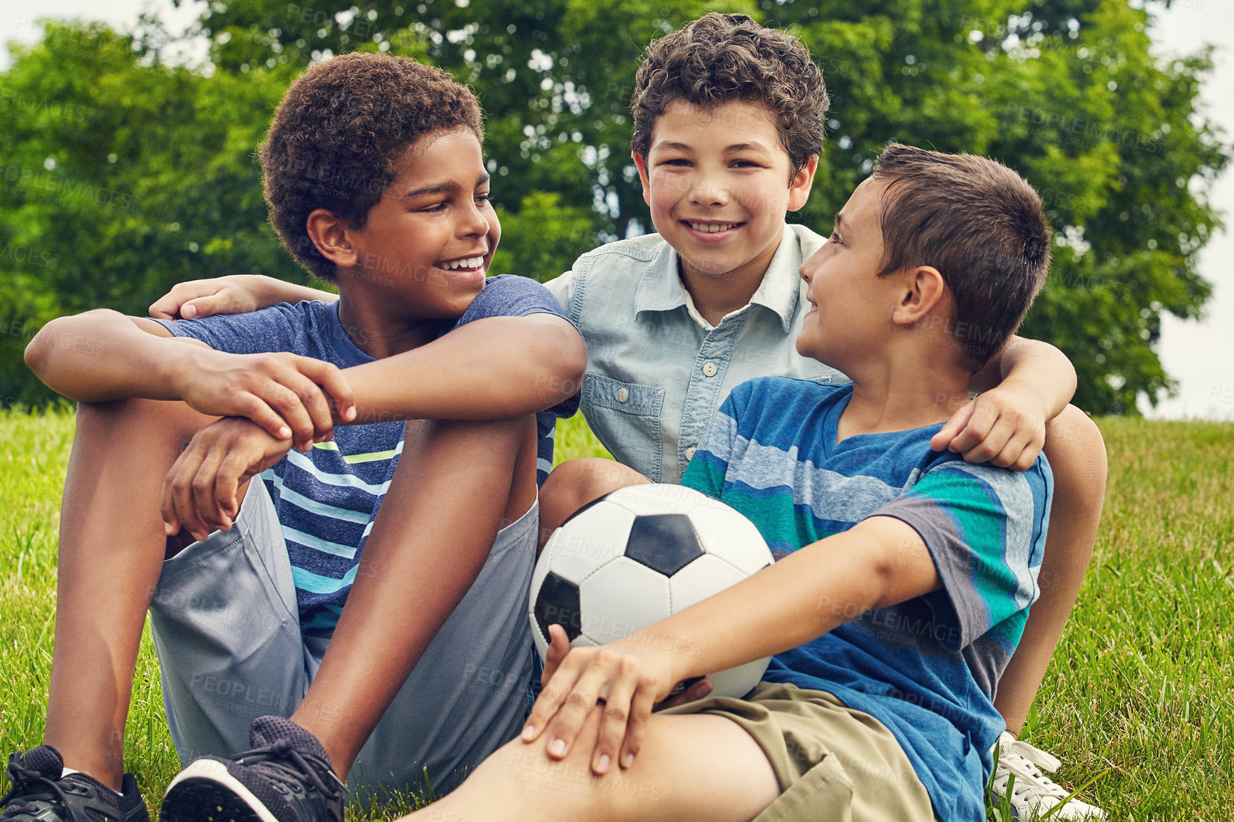 Buy stock photo Friends, children and sitting in field with soccer ball for happiness, development or bonding together. Nature, diversity and boy kids with smile in park for freedom, support or relax on weekend