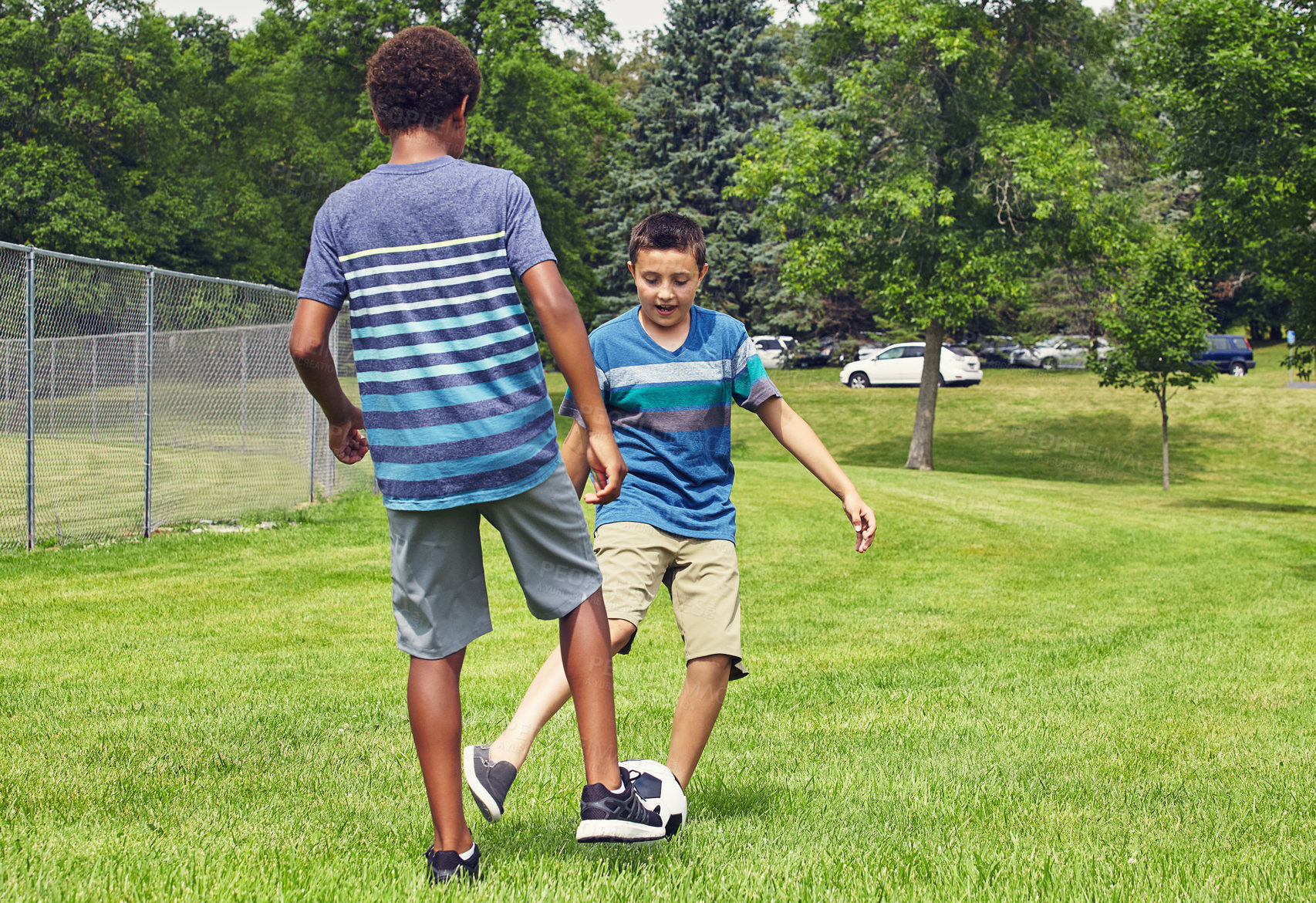 Buy stock photo Shot of two young boys playing a game of soccer in the park