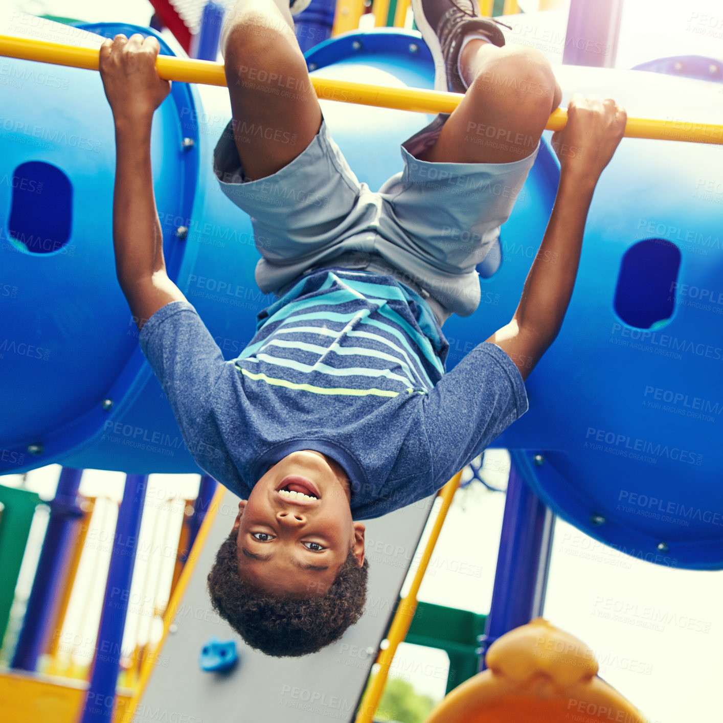 Buy stock photo Shot of a young boy hanging upside down on a jungle gym in the park