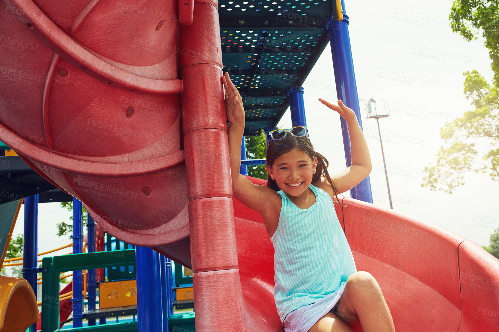 Buy stock photo Shot of a young girl sliding down the slide on a jungle gym in the park