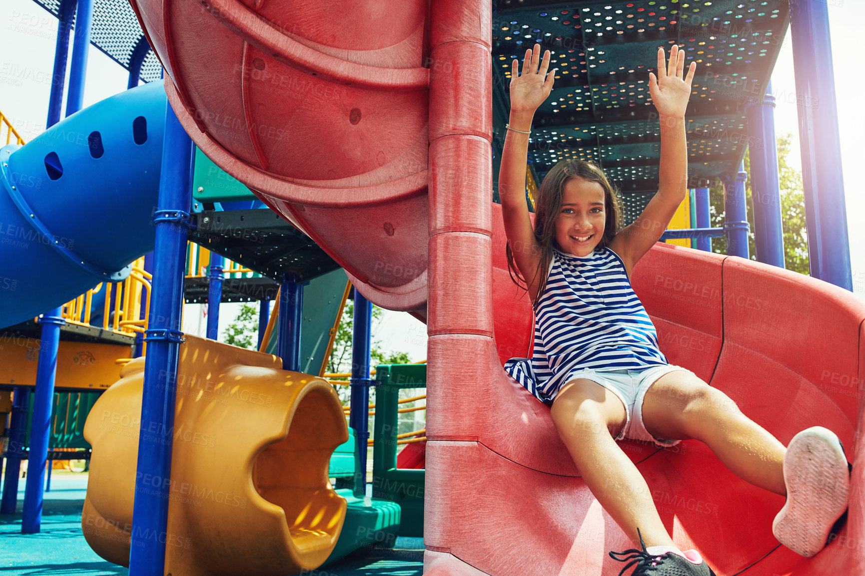 Buy stock photo Shot of a young girl sliding down the slide on a jungle gym in the park