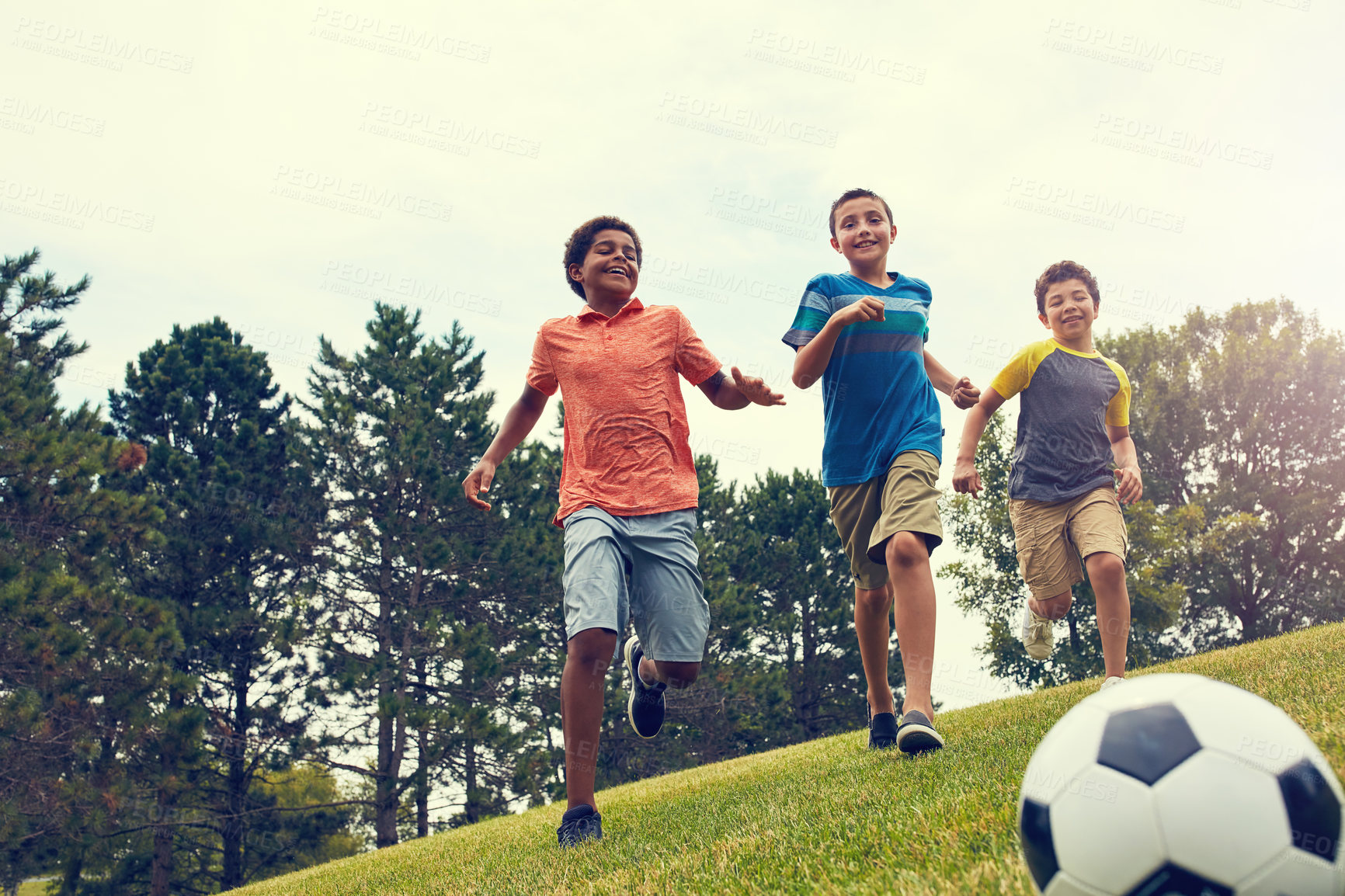 Buy stock photo Soccer ball, running and boy children in park for bonding, games and outdoor holiday together. Sports, kids and happy friends playing on grass with smile, fun and energy on summer camp for football.