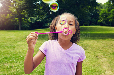 Buy stock photo Cropped shot of a little girl blowing bubbles outdoors
