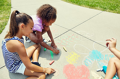 Buy stock photo Shot of adorable little girls drawing with chalk on the pavement outdoors